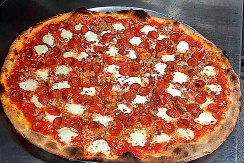 Margherita pizza with red tomato sauce, fresh mozzarella dollops, and herbs on a charred crust